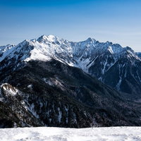 春なお雪深い穂高連峰と雪道の北アルプス山岳風景の写真