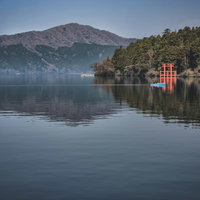 箱根神社の朱色の鳥居と芦ノ湖の釣り船の風景の写真