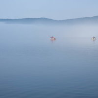 霧が立ち込める芦ノ湖の水面に浮かぶ釣り船の写真