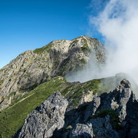 八峰キレットの岩稜に立ち上がる雲と青空の登山風景の写真