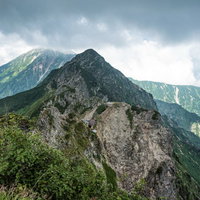 八峰キレット、崖に建つ山荘と稜線、雲海と岩壁の景観の写真