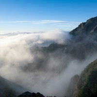 キレット縦走で見る山に流れ込む雲海と稜線の写真