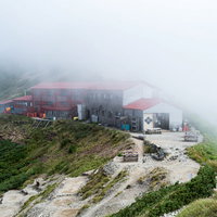 霧が立ち込める稜線上の山荘の写真