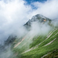 八峰キレット縦走の傾斜にかかる雲と尾根の山岳風景の写真