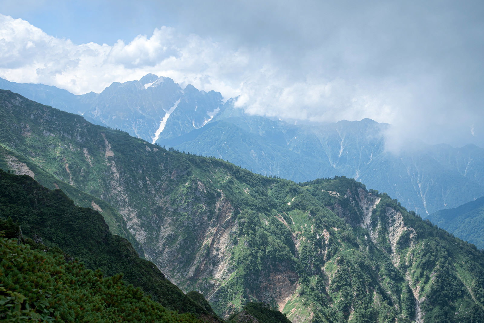 雲が立ち込める険しい山々の連峰を撮影した風景写真