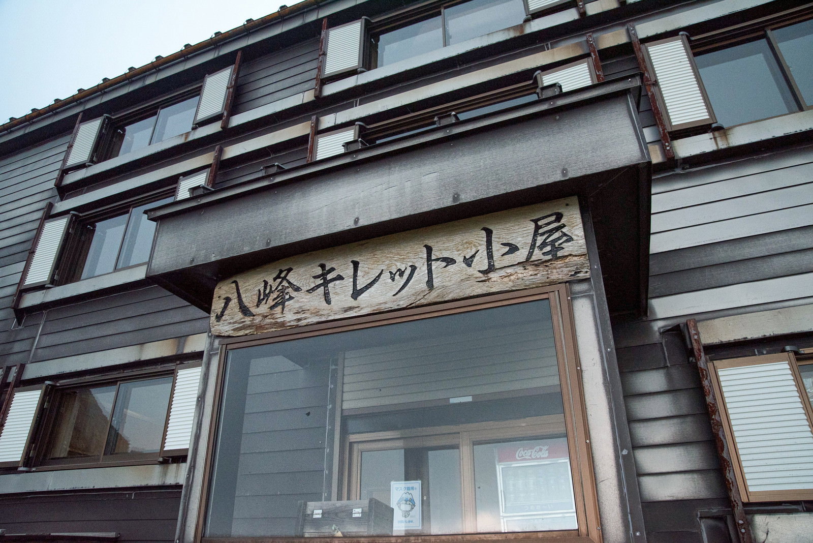 八峰キレット小屋の入口付近に設置された看板と木造建物の外観