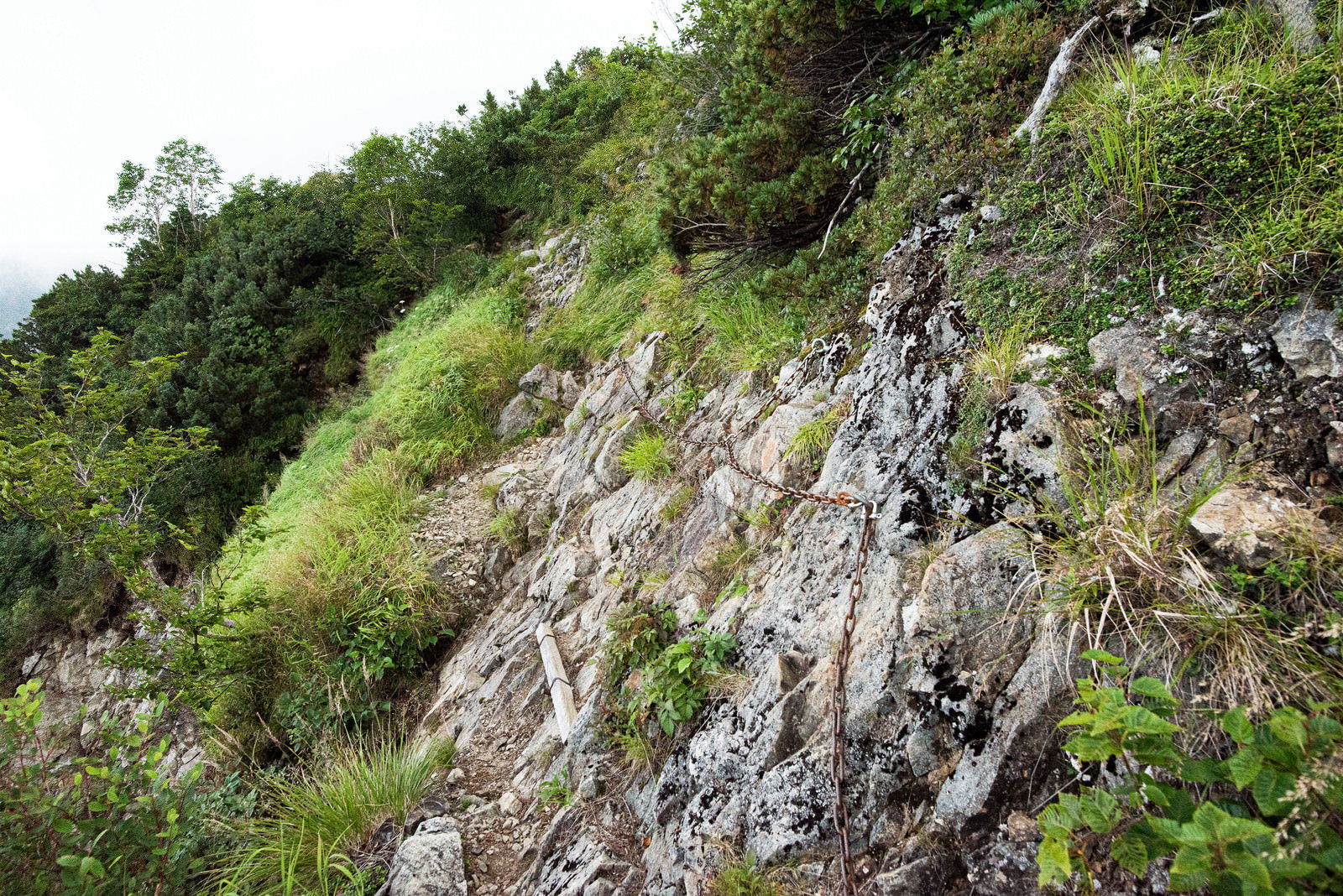 急峻な岩肌に鎖が設置された足場の悪い斜面の鎖場