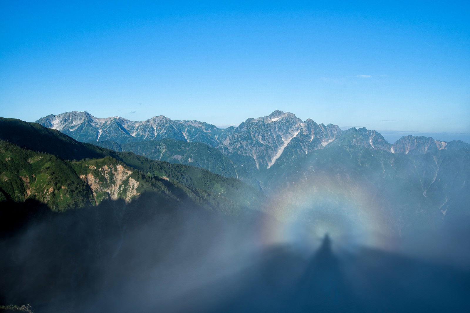 雲海の上に浮かぶ山々を背景に光輪現象が現れた風景