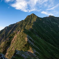 日を浴びる傾斜面と影が織りなす山稜線の登山風景の写真