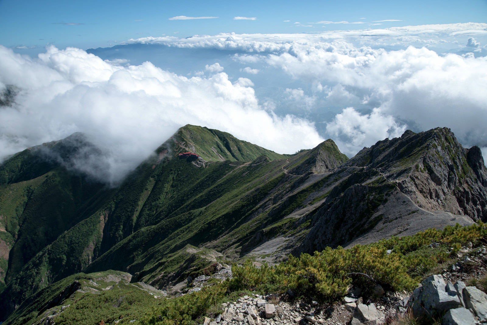 登山道の先に山荘が見える稜線と雲海が広がる山岳風景
