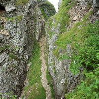 八峰キレットの岩壁に挟まれた登山道を行く登山者の写真