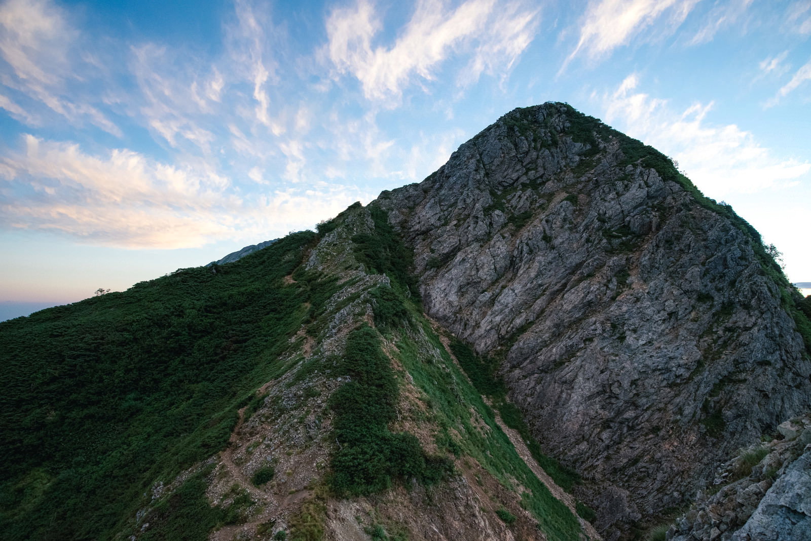 青空をバックに登山道脇にそびえる巨大で険しい岩稜
