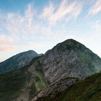 夕焼け色に染まる八峰キレットの岩稜と登山道の写真