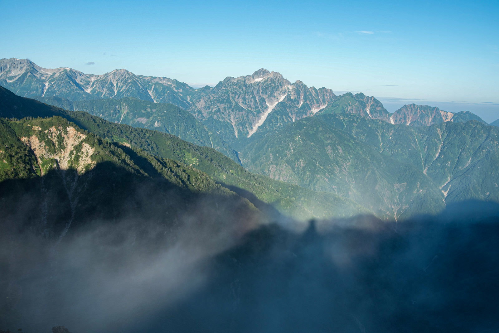 朝霧に包まれた山々の尾根と青空が広がる風景