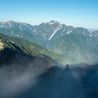 朝霧の尾根に伸びる登山者の影と八峰キレット縦走路の写真