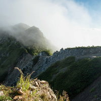 雲にまみれた八峰キレットの尾根の山肌と登山道の写真