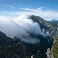 長く伸びる稜線に覆いかぶさる雲と連峰、八峰キレットの写真