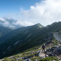 どこまでも続く稜線と登山道を歩む登山者たちの姿の写真