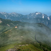 八峰キレットの登山道の先に見える山荘と連峰の写真
