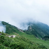 稜線を飲み込もうとする大量の雲と登山道の絶景の写真