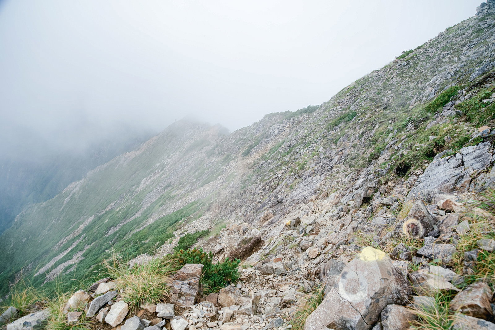 霧に包まれた険しいガレ場の登山道を写した風景