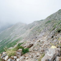 雲に覆われるガレの続く登山道、八峰キレット縦走の険しい岩場の写真