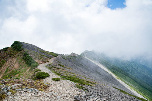 雲の中に消えゆく登山者と八峰キレットの稜線