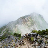 沸き立つ雲に覆われる足場の悪い八峰キレット登山道の写真