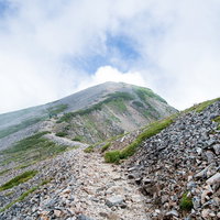 沸き立つ雲の中へと続く八峰キレットのガレの登山道の写真