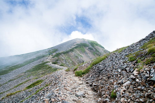 沸き立つ雲の中へと続く八峰キレットのガレの登山道