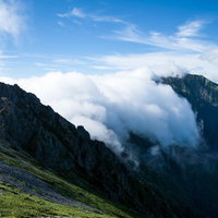 八峰キレットの岩稜を乗り越えて流れ込む雲の写真