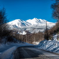 乗鞍岳へと続く残雪の道路と雪化粧した山々の写真
