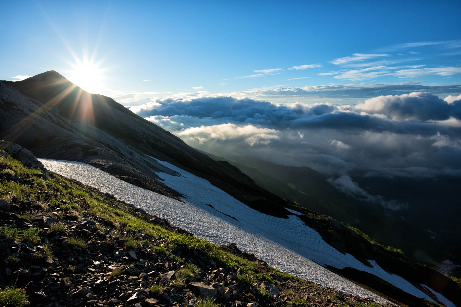 朝日が差し込む北アルプスの稜線を歩く登山道と雲海の風景
