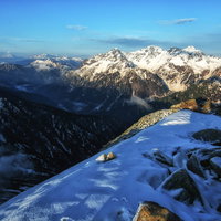 常念岳山頂からの残雪と雪山の風景の写真
