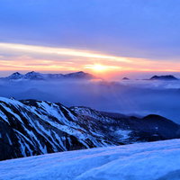 冬の雪山から望む夜明けの日の出の写真