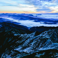 残雪の山々と雲海を眺める登山者の写真