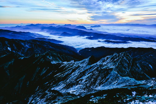 残雪の山々と雲海を眺める登山者