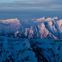 朝焼けに染まる雪の北アルプス連峰の夜明け風景の写真