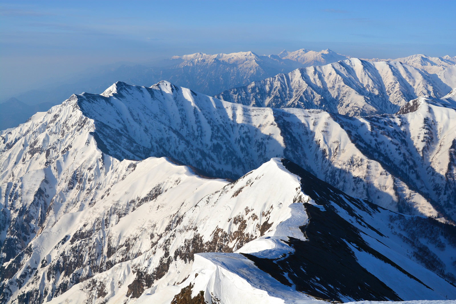 雪に覆われた爺ヶ岳と北アルプスの山々が青空の下に連なる風景