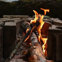 ブロック塀の上で燃える焚火の炎と薪の写真