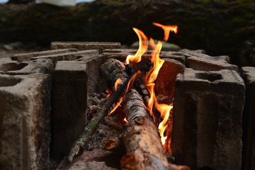 ブロック塀の上で燃える焚火の炎と薪
