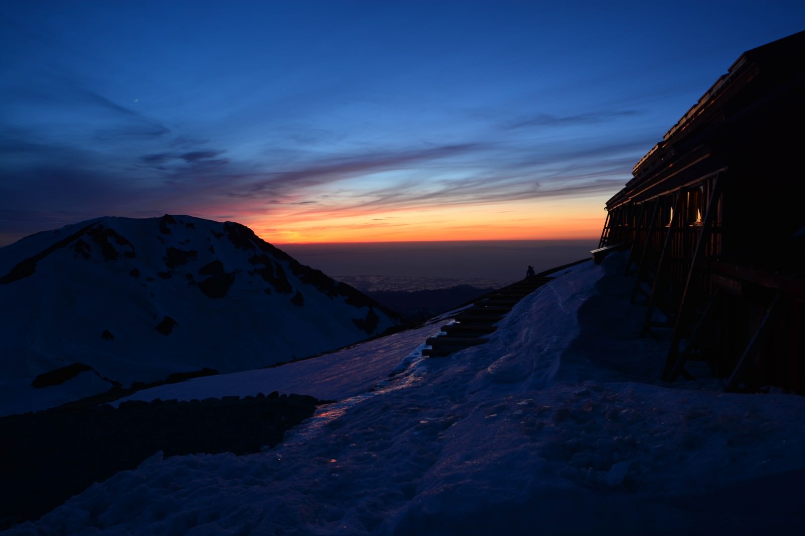 夕焼け空にシルエットで浮かび上がる白馬山荘と山の稜線