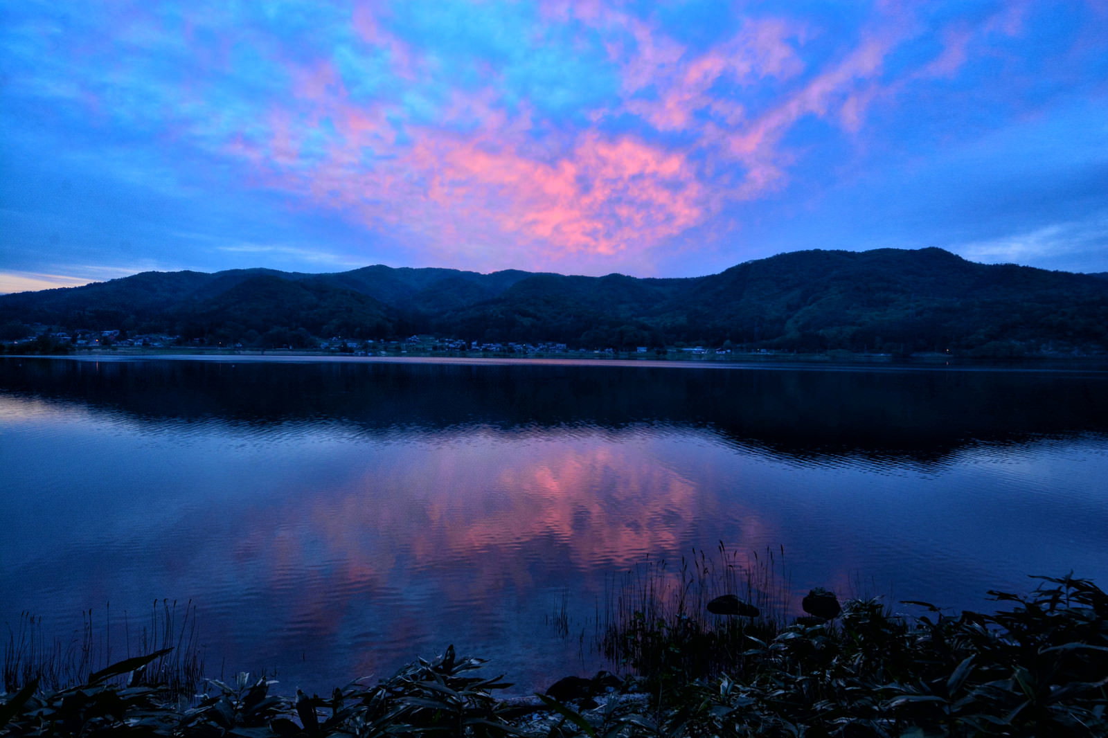 湖畔の水鏡に映るリフレクションした夕焼けの空の写真素材 - フリー