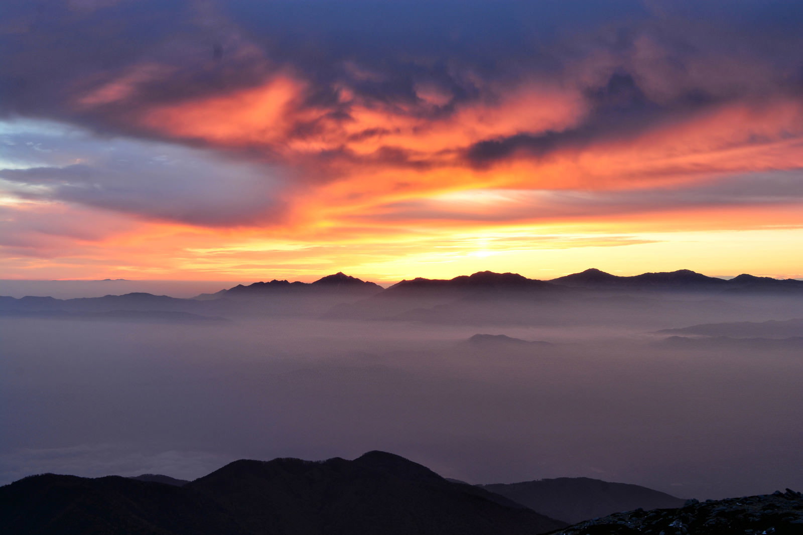 夕焼け空をバックに南アルプスの山々のシルエットと雲海が広がる風景