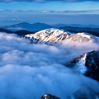 雲に飲み込まれる蝶ヶ岳の雪山、北アルプスの冬景色の写真