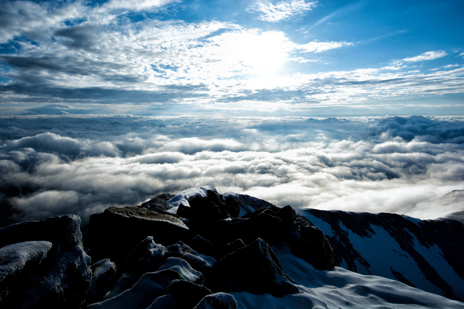 山頂から見下ろす雲海と雪に覆われた山脈の風景