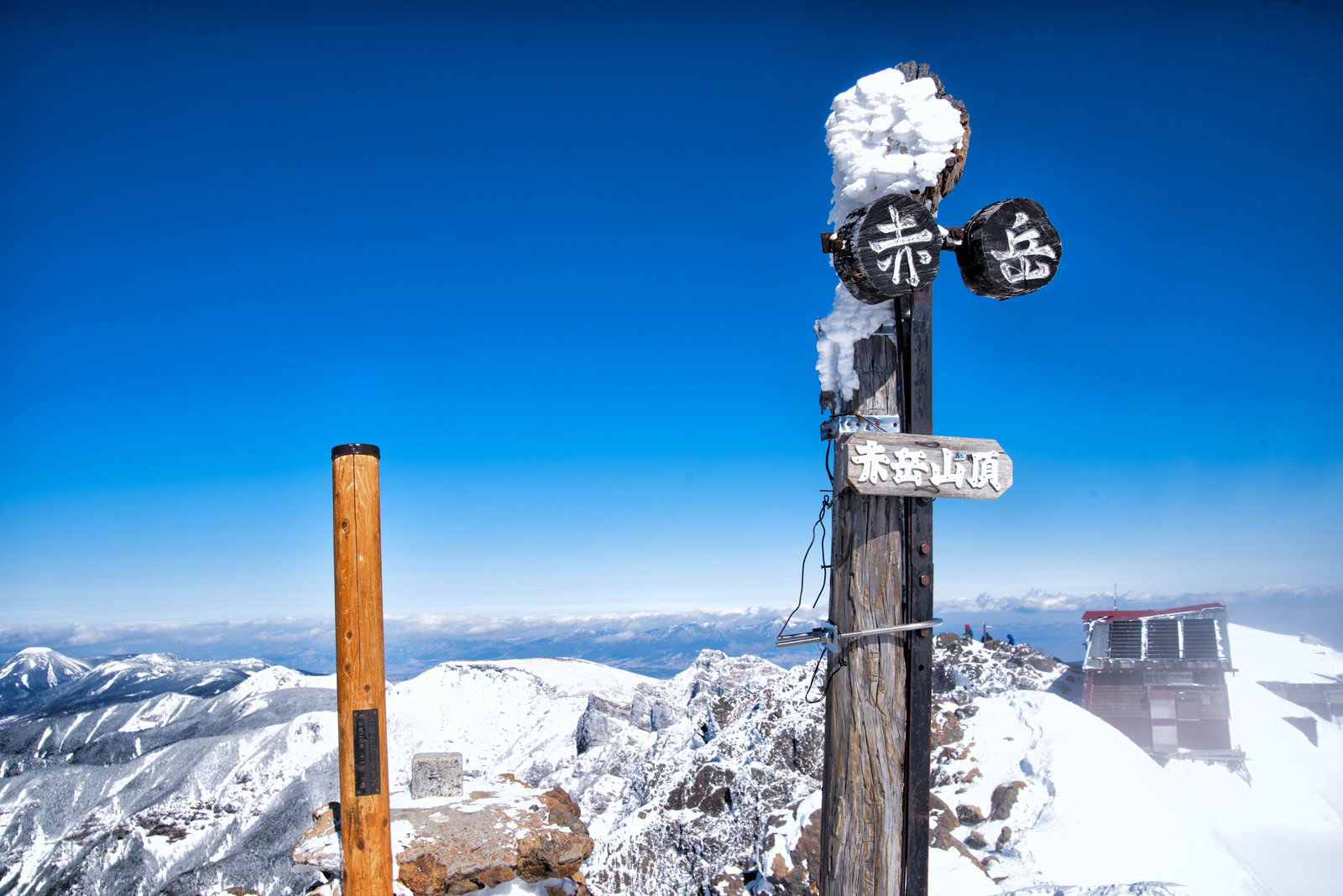 雪に覆われた赤岳山頂に立つ道標と青空の風景