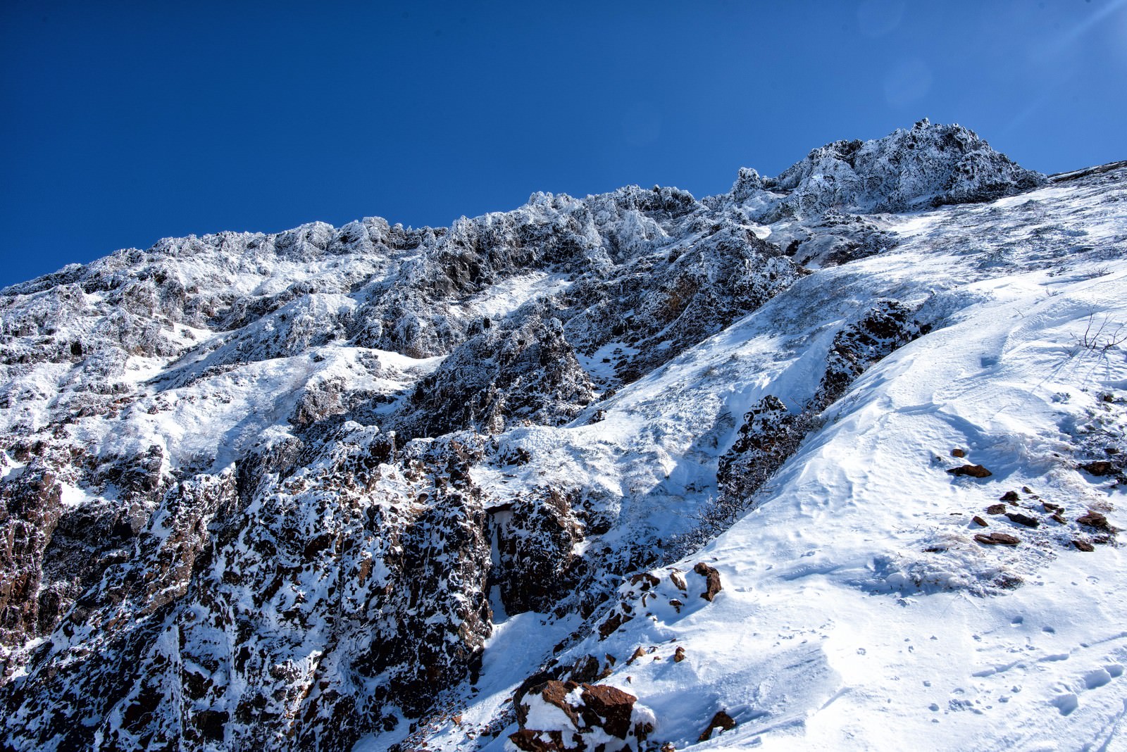 雪に覆われた急峻な岩壁を登る登山者