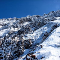 山頂直下の岩壁を行く冬山登山の写真