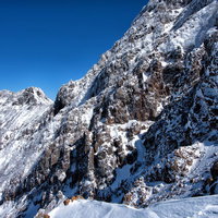 冬の赤岳、雪に覆われた険しい岩壁と青空、標高の高い山岳地帯の写真